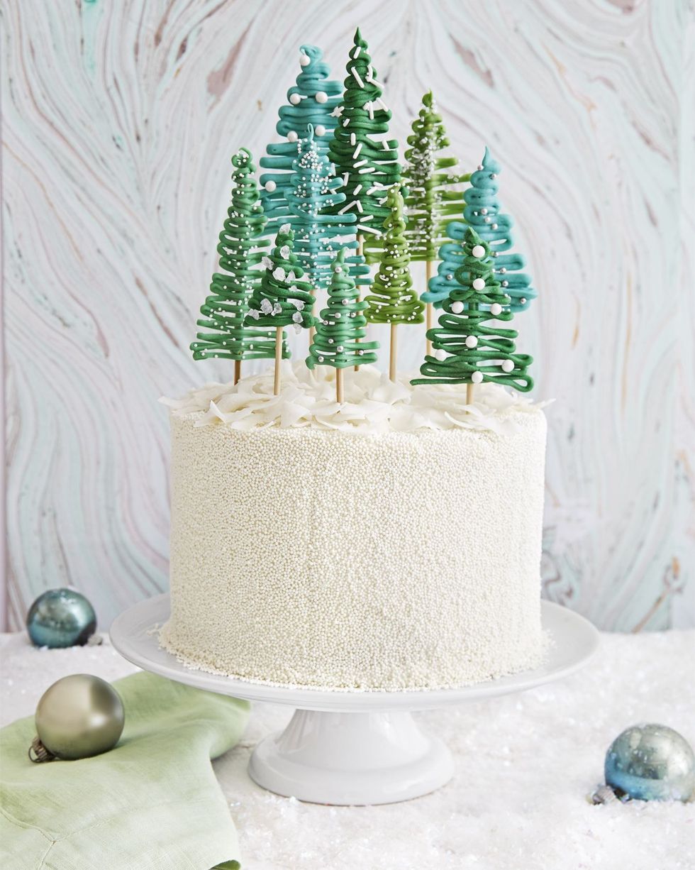 white christmas cake garnished with various christmas trees on top