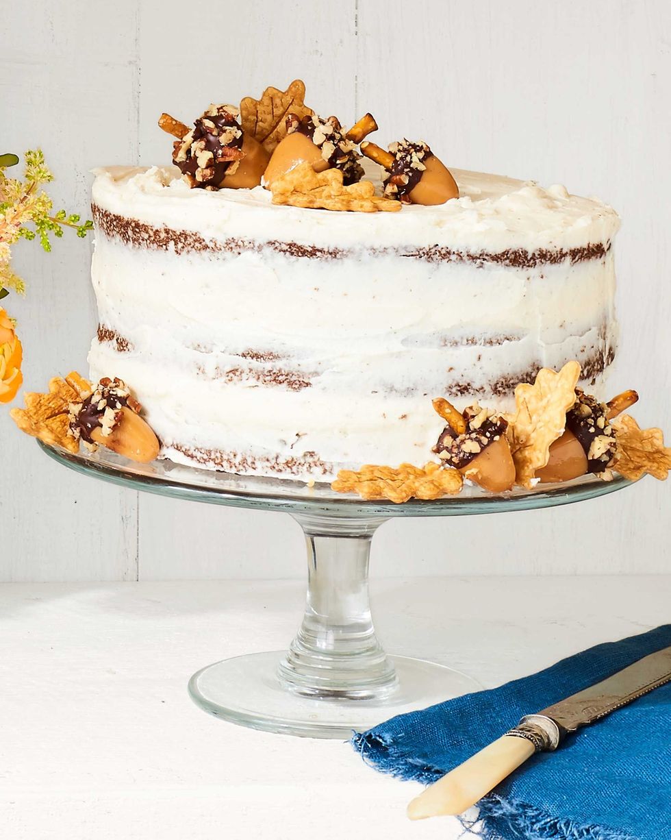 spice layer cake on a glass cake stand and garnished with pie crust leaves and acorn cookies