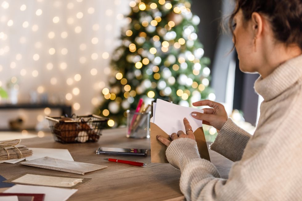 young woman putting christmas card in envelope