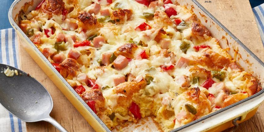 christmas casserole with peppers and ham on wood board with metal spoon