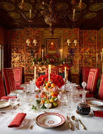 a dramatic gold and red dining room has a table set with fancy tableware and a cluster of bright red amaryllis flowers