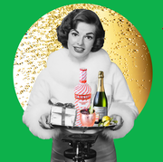 a woman holding a tray of champagne, smirnoff, and a present on a green and gold christmas like background