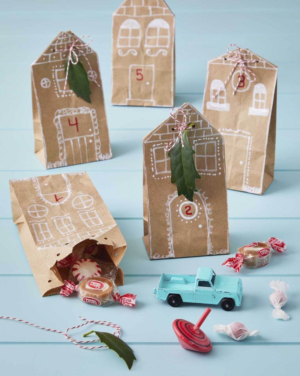 brown paper lunch bags with houses drawn on them filled with candy and toys and used as an advent calendar