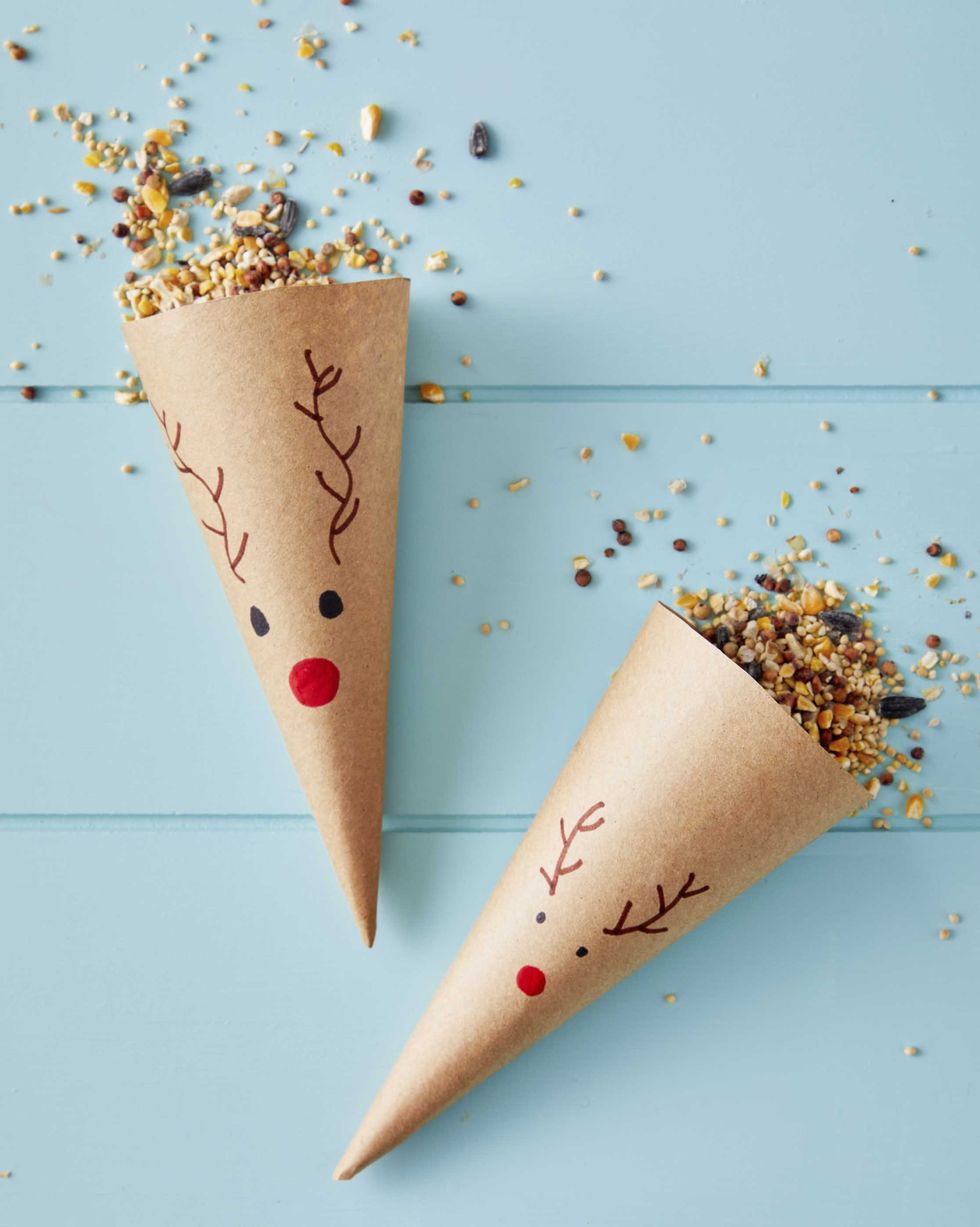 brown kraft paper cones with a reindeer face drawn on the front and filled with birdseed