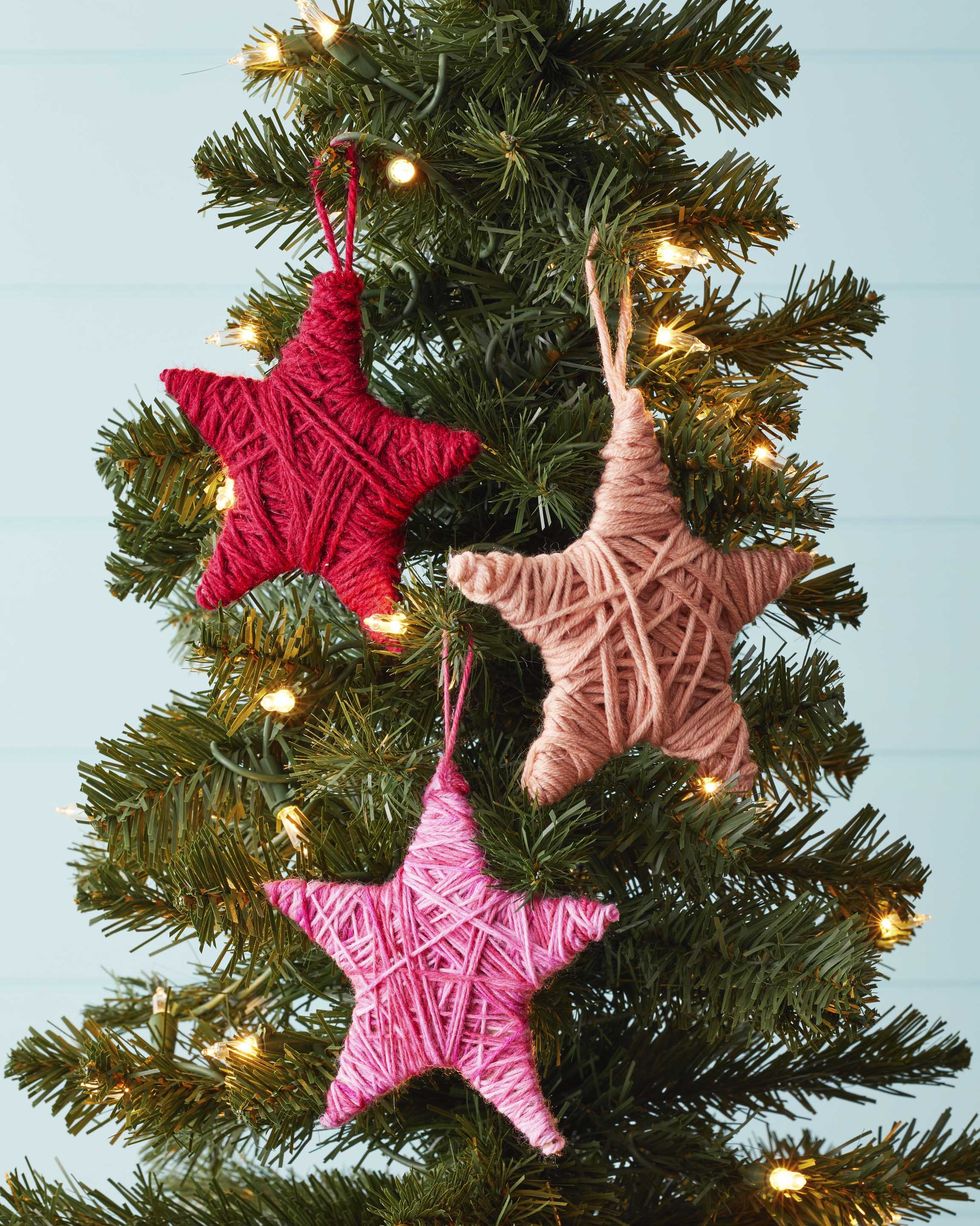 ornaments shaped like stars covered in colorful yarn hung on a tree