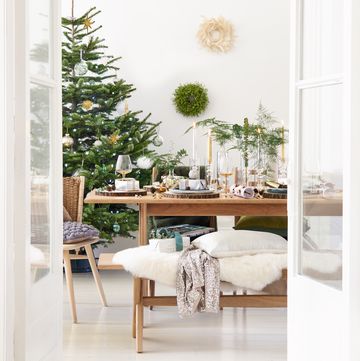 cover shot, wooden dinning table with a christmas tree in the corner of the room