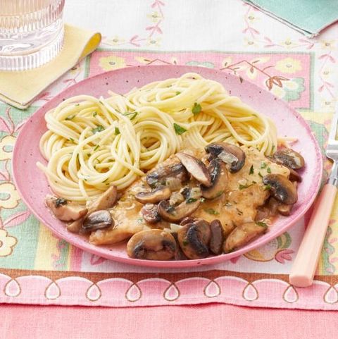 chicken marsala with mushrooms and spaghetti on pink plate