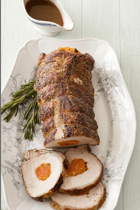 apricot stuffed pork loin on a white oval serving plate with rosemary