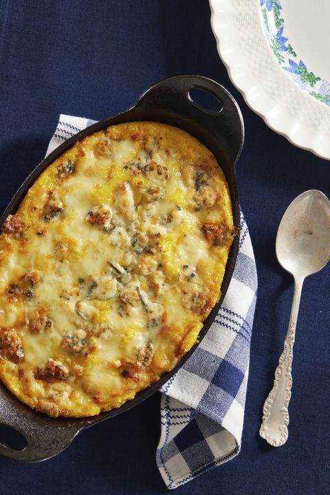 gorgonzola baked polenta in an oval baking dish with a spoon for serving