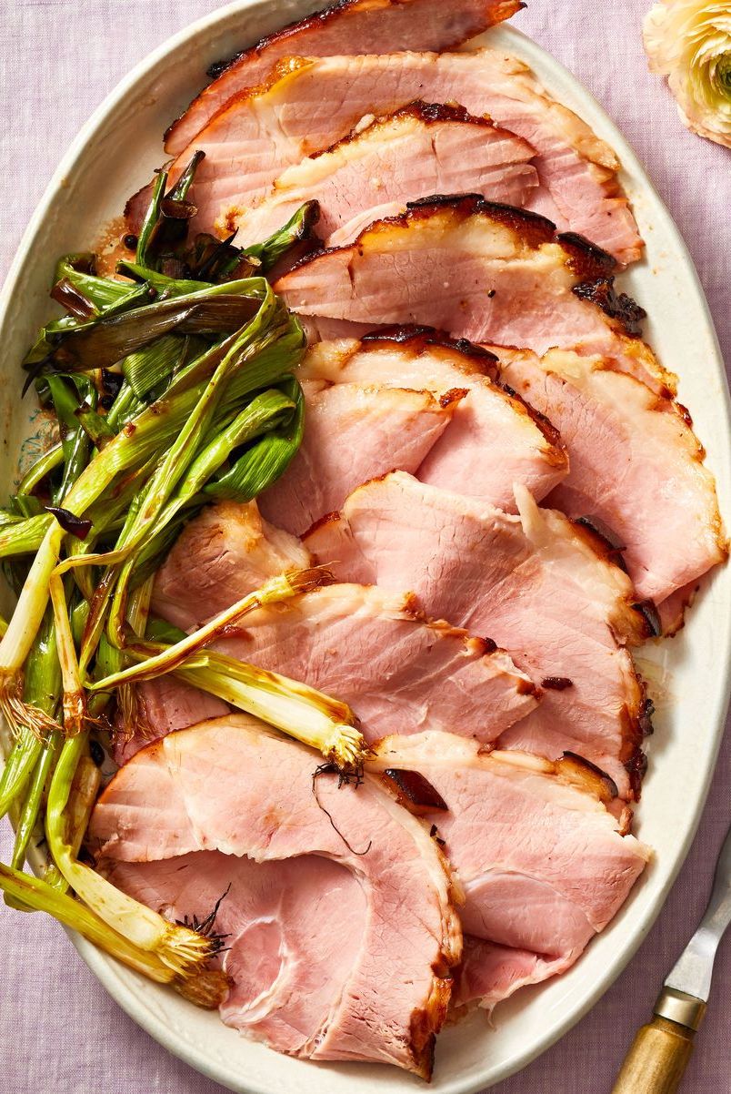 slices of glazed ham with roasted scallions on the side