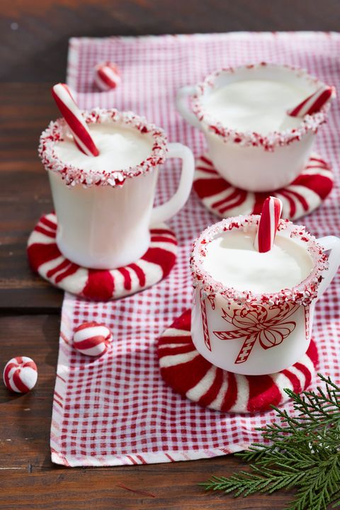 three festive mugs of peppermint eggnog with a candy cane in each