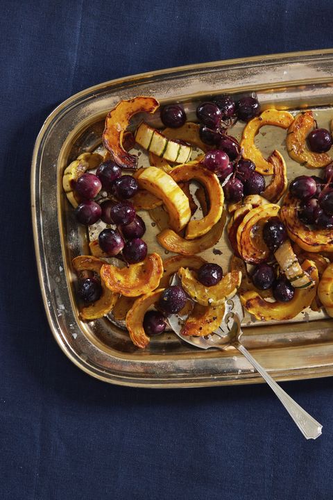 roasted grapes and delicata squash rings on a silver serving tray with a silver spatula for serving