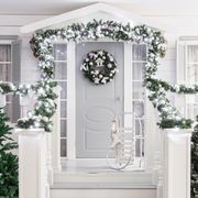house entrance decorated for holidays christmas decoration garland of fir tree branches and lights on the railing