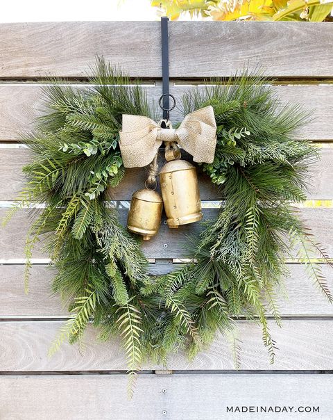 christmas door decorations, evergreen wreath with gold bells hanging from a fence