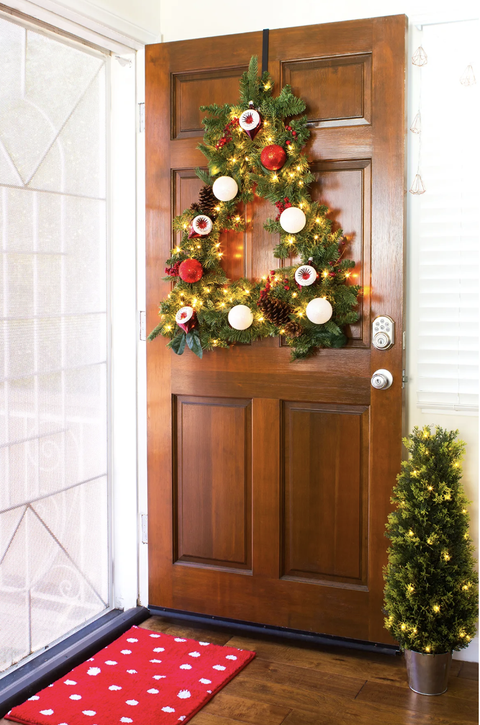 christmas door decorations, tree shaped wreath with ornaments and lights hanging on the front door