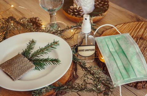 christmas eve holiday party decorated table set with disposable medical mask and alcohol hand sanitizer bottle coronavirus covid 19 spreading prevention concept christmas micro led lights wire