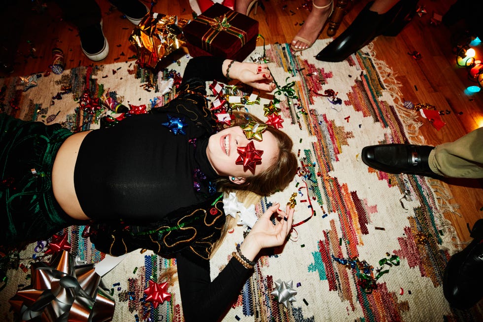 woman laughing and lying on the floor with bows over eyes during a holiday party with friends