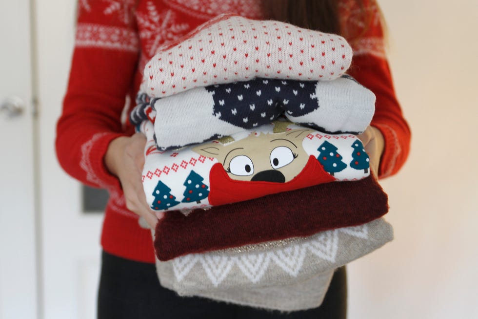 close up of woman holding stack of folded sweaters