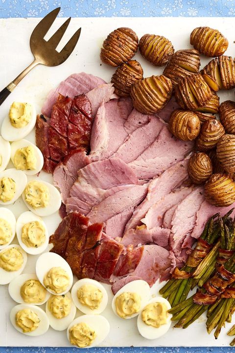 honey mustard glazed ham sliced on board with eggs, potatoes, and asparagus