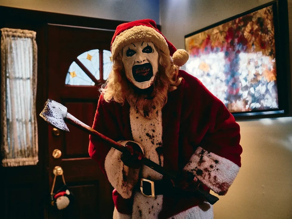 a figure dressed in a santa costume holding an axe in a scene from terrifier 3