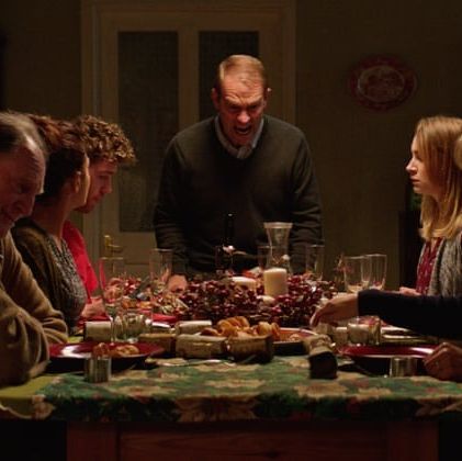 a group of people sit around a table in a scene from await further instructions