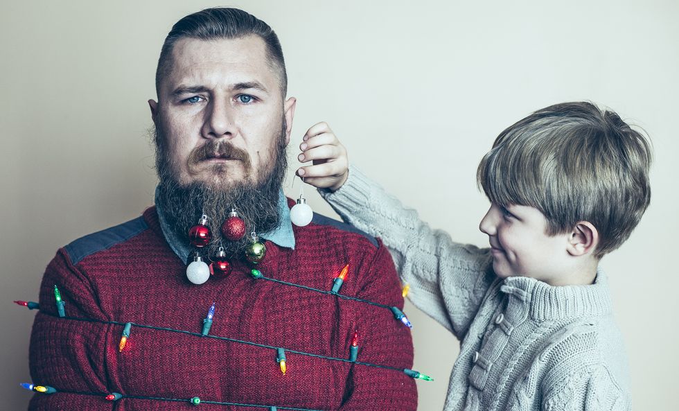 little boy having fun decorating his near agony full of despair very overwhelmed by holiday season dad as a christmas tree