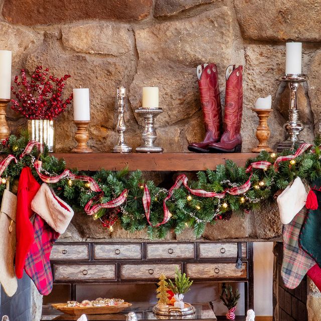 christmas mantel decorated with garland, ribbon, candles, and cowboy boots