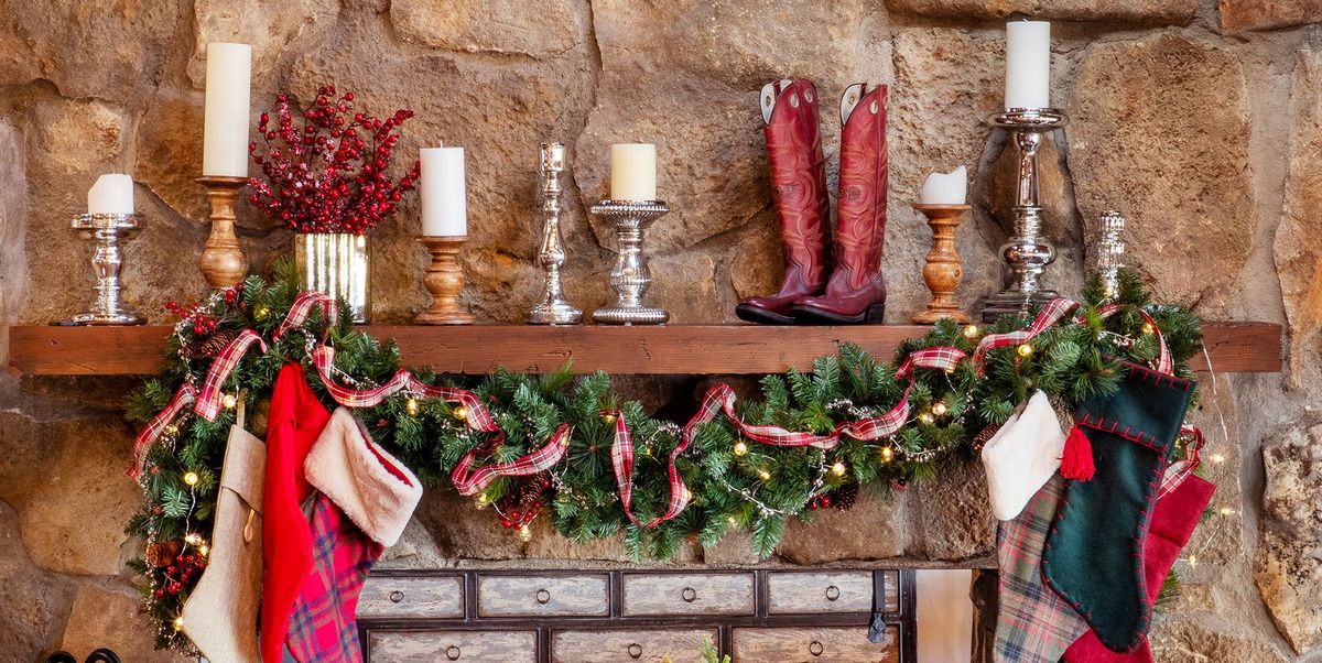 christmas mantel decorated with garland, ribbon, candles, and cowboy boots