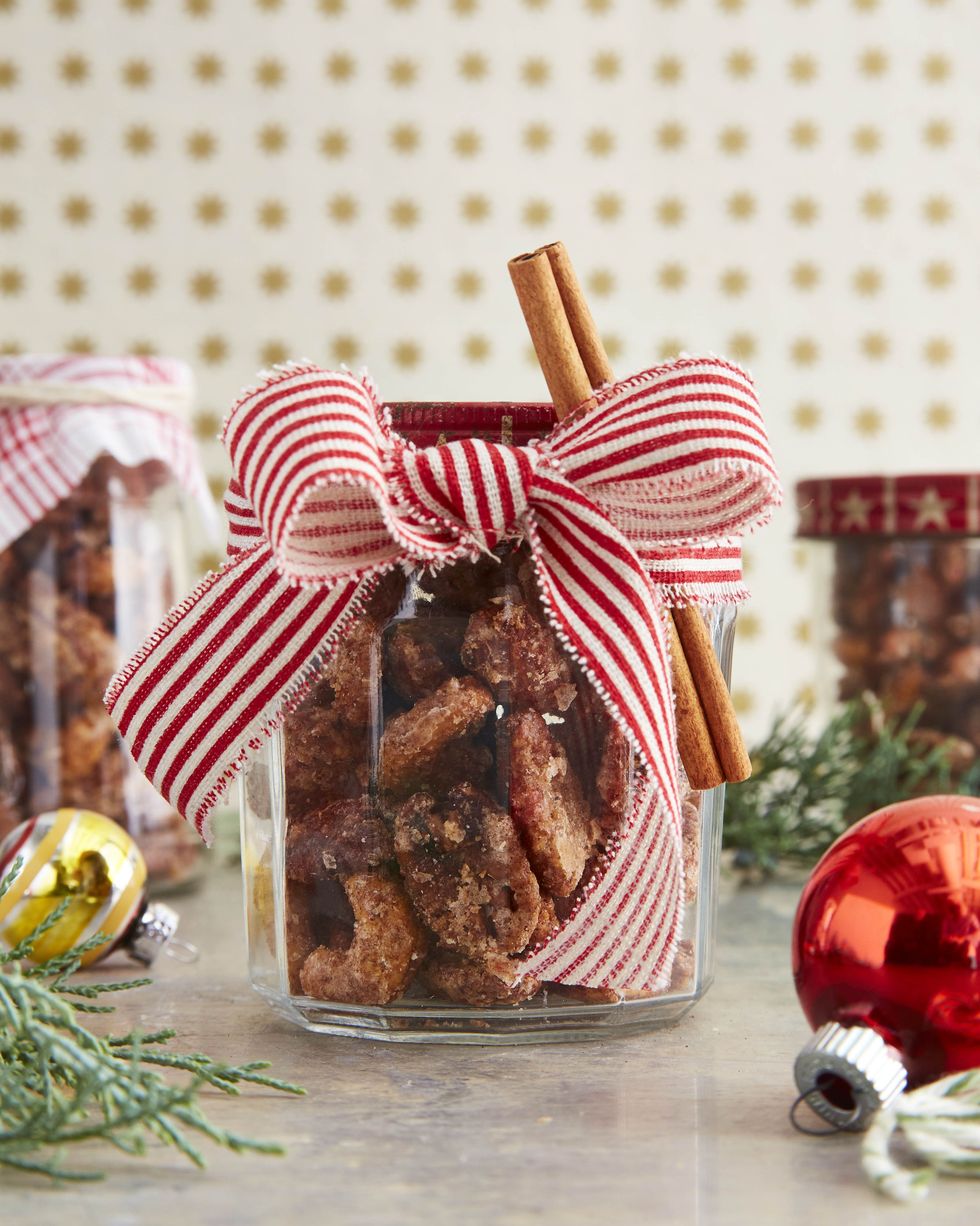 cinnamon and cayenne coated nuts in jar decorated with red and white striped cotton ribbon and cinnamon stick for a christmas gift