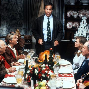 chevy chase stands at the head of the table in a scene from the film christmas vacation