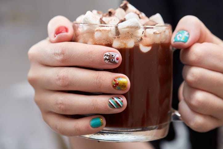 female hands with bright festive manicure design holding glass mug with hot cocoa and marshmallows winter holidays christmas and new year