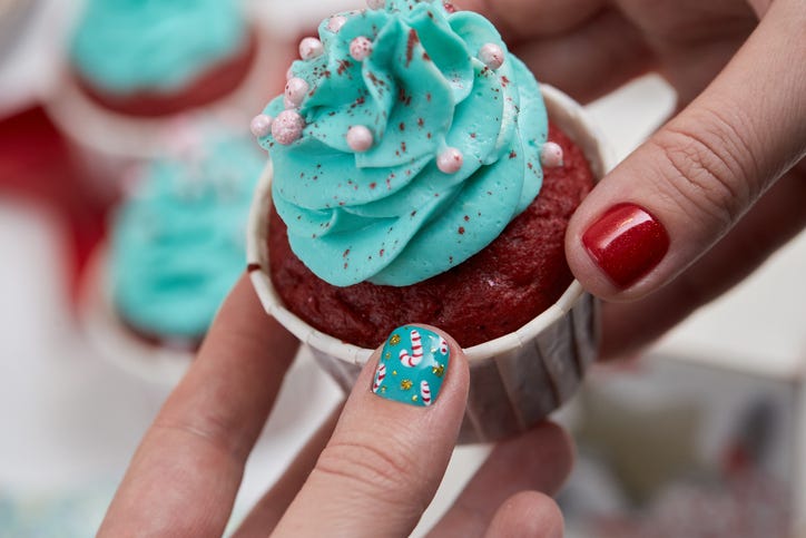 female hand with festive  christmas manicure  holding tasty cupcake christmas and new year treat