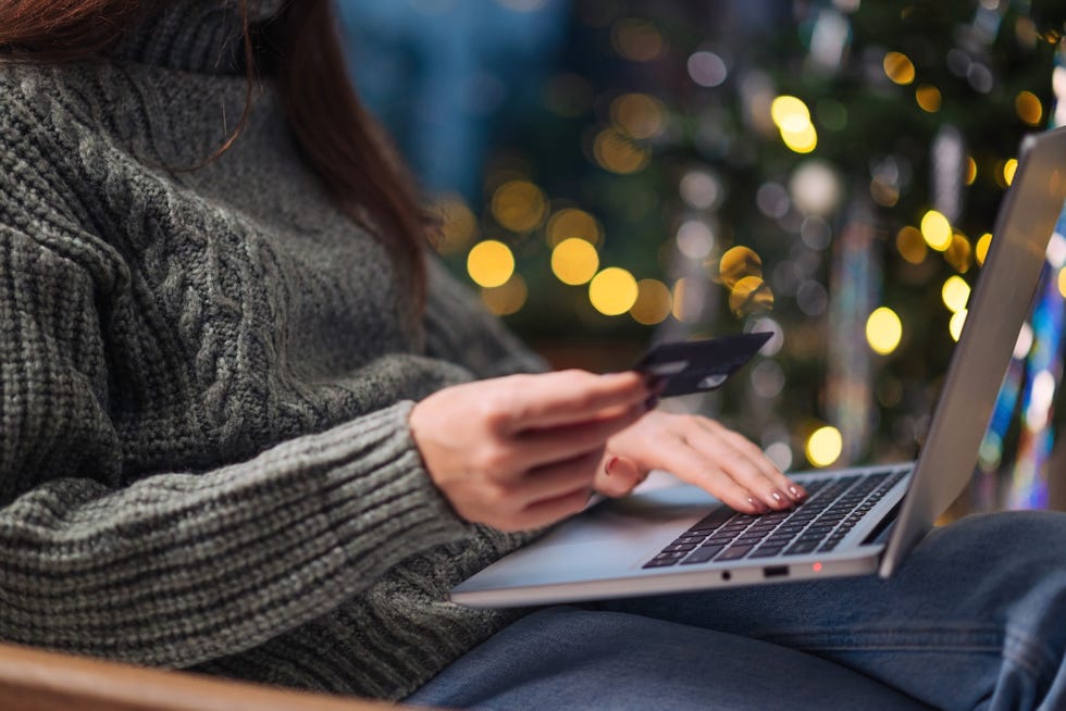 christmas online shopping, sales and discounts promotions during winter holidays, online shopping at home female hands on the laptop with credit card and blurred bokeh lights