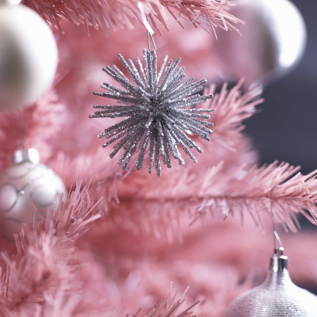 Christmas ornaments on pink Christmas tree, close-up