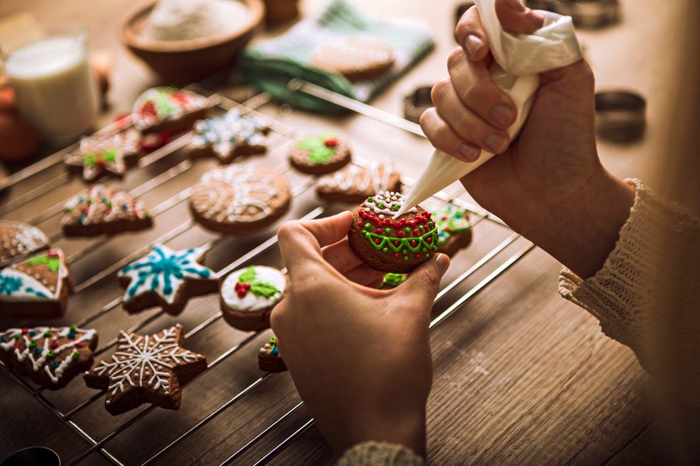 close up of a woman's hands decorating christmas cookies