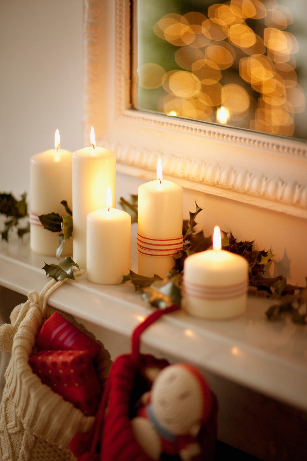 candles lit on a mantelpiece with christmas stockings