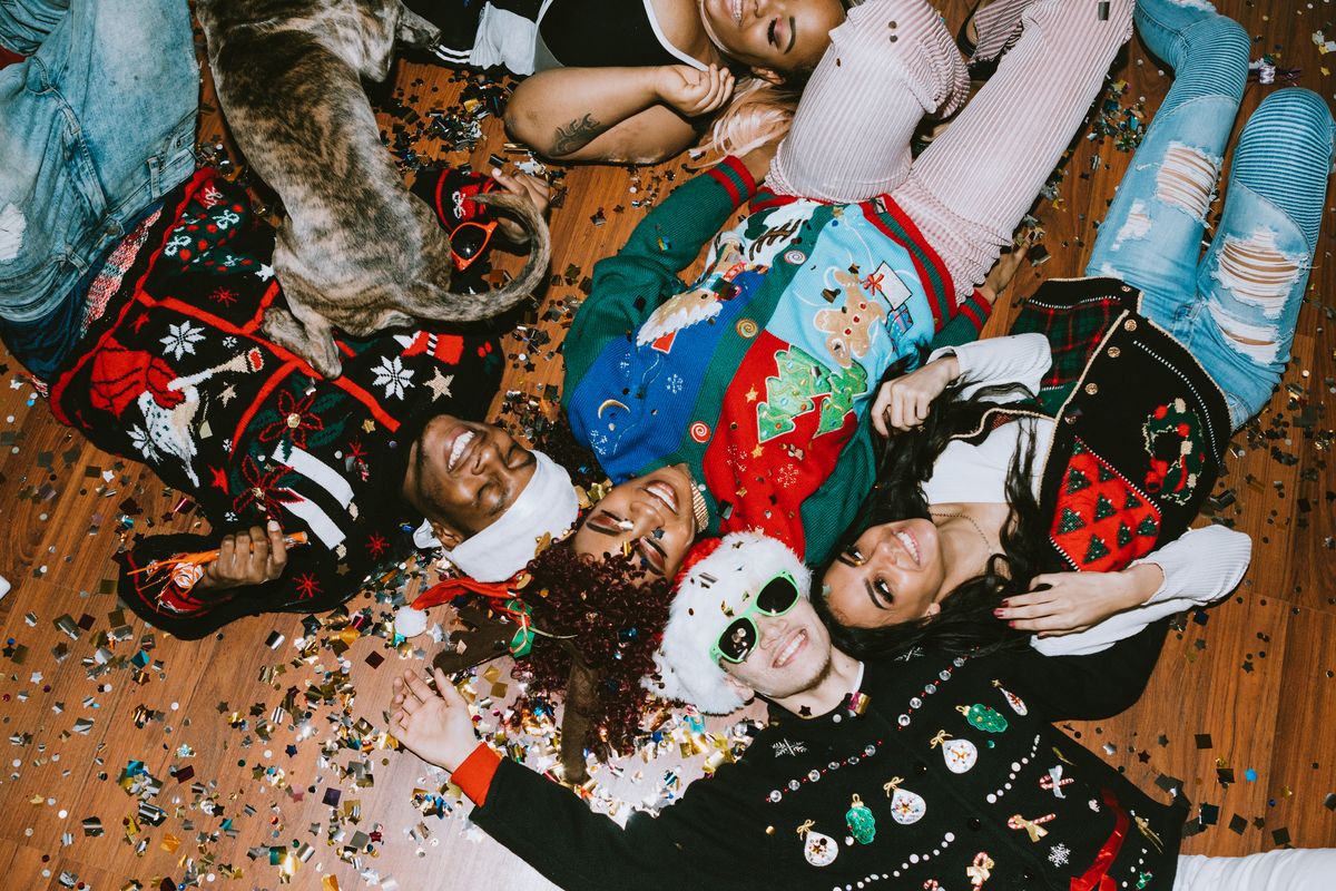 christmas party themes where friends are laying on the floor covered in glitter, while wearing holiday themed accessories