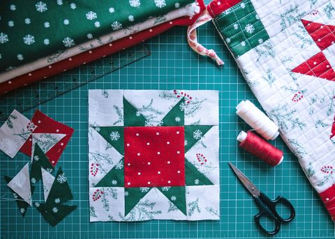 christmas patchwork red star block fragment of quilt, sewing accessories, space for text on green background