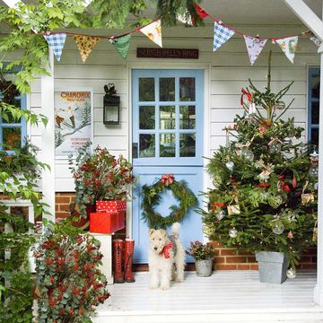 front porch with christmas holiday decorations   christmas tree, wreath, dog with bow