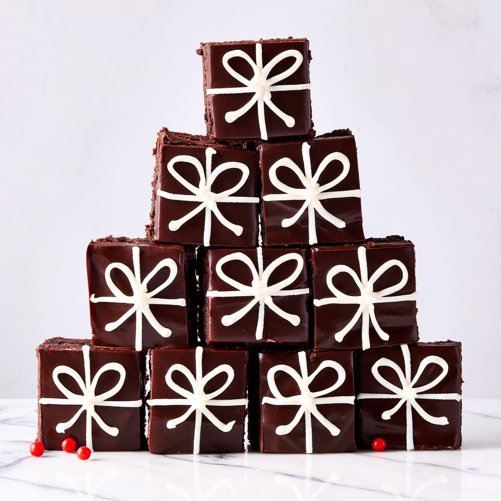 brownie bites cut into squares, topped with ganache, and decorated like christmas presents with white icing