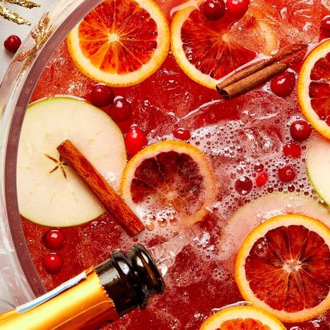 red christmas punch filled with sliced blood oranges, cinnamon sticks, sliced apples, and fresh cranberries