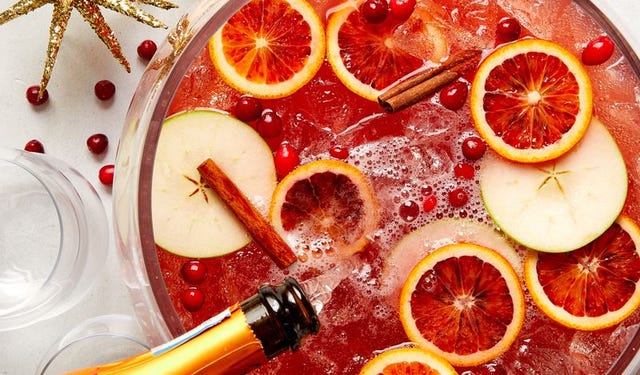red christmas punch filled with sliced blood oranges, cinnamon sticks, sliced apples, and fresh cranberries