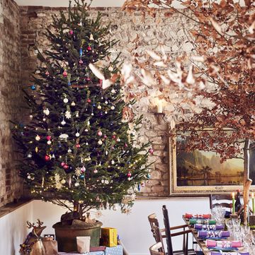 sarah moore's farmhouse at christmas large christmas tree with presents and large dining table set with crackers large tree centerpiece