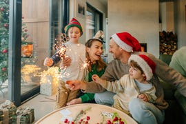 family celebrating during the holidays wearing santa hats while holding sparklers