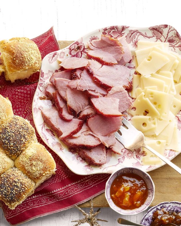 honey glazed ham and checkerboard rolls on platter with cheese and spreads