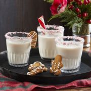 three glasses of eggnog with gingerbread cookies on a black tray