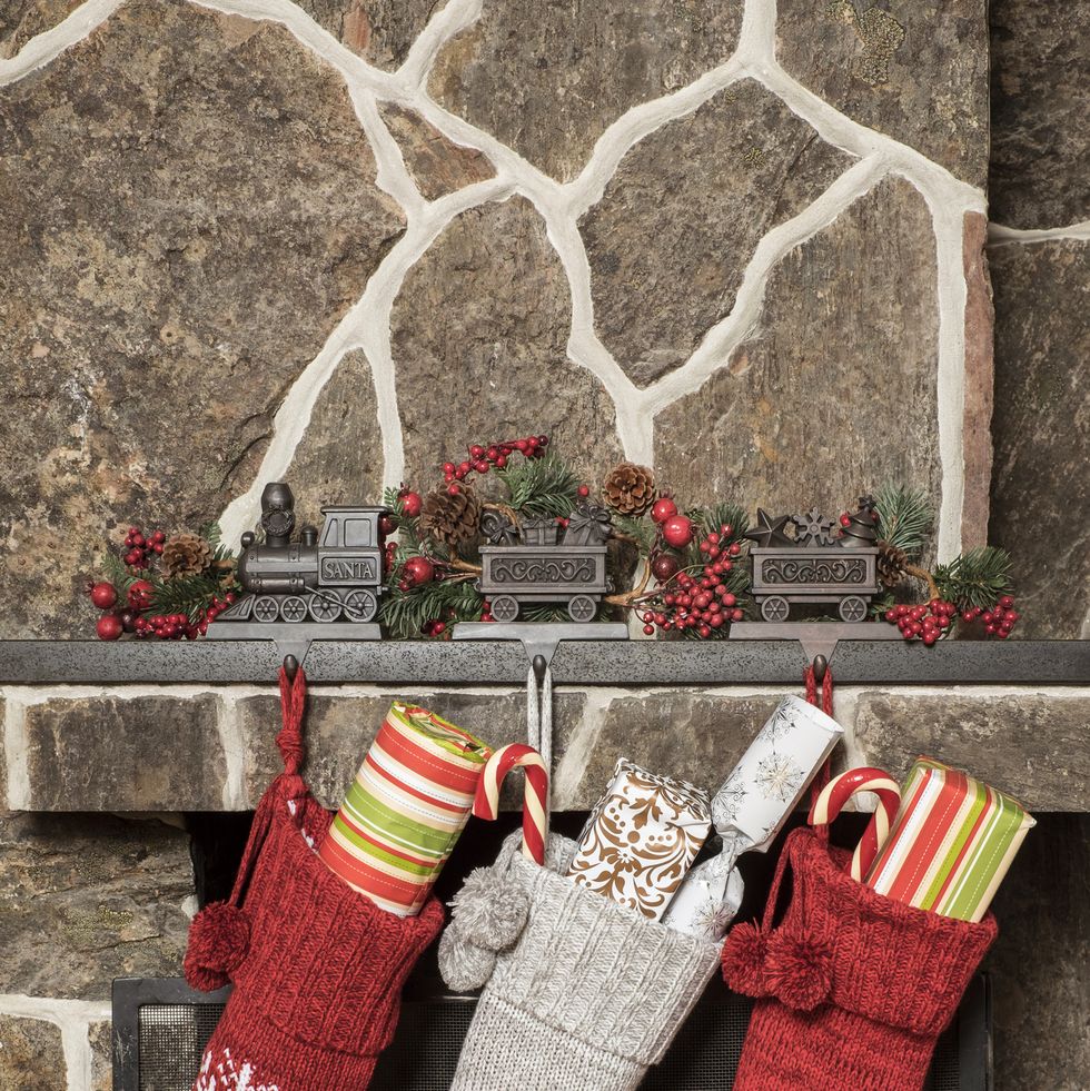 red and gray stockings with presents inside hung by a brick fireplace