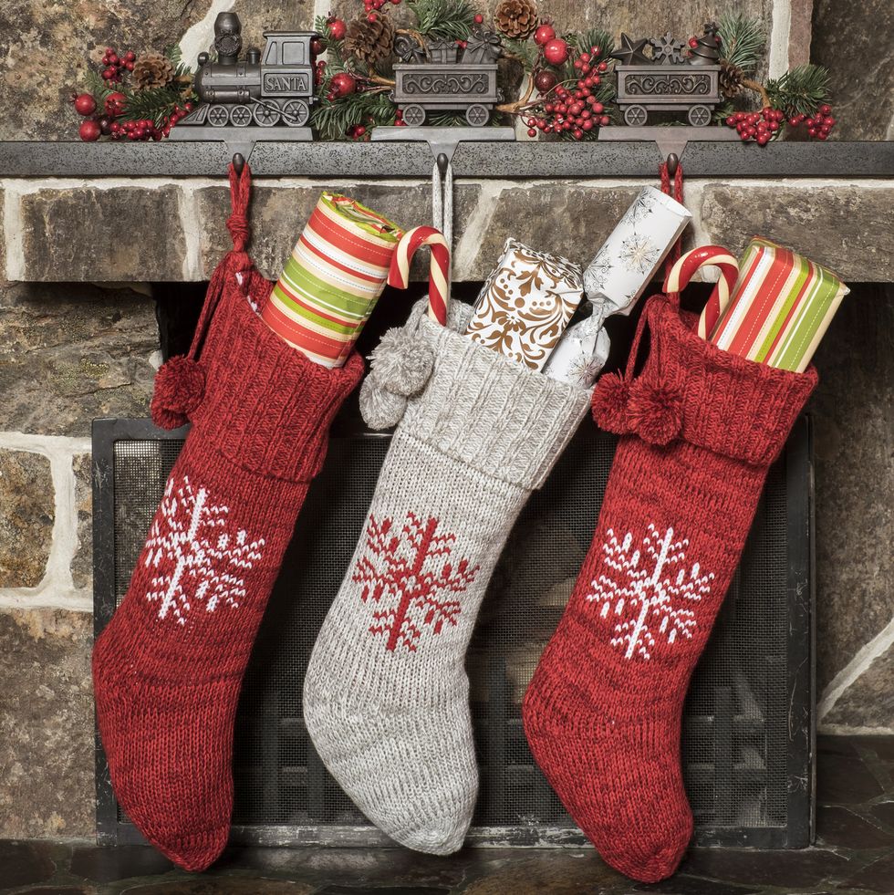 red and gray stockings with presents inside hung by a brick fireplace