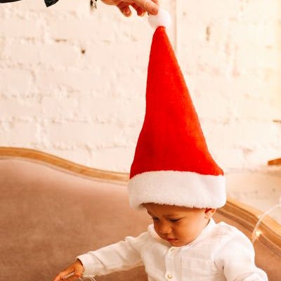 child with a red santa hat and playing with christmas lights