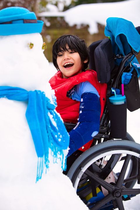 child in wheelchair with a snowman
